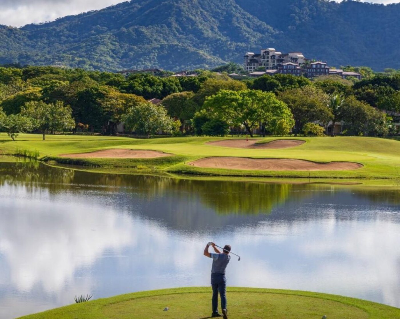A golfer teeing off over the water on the Robert Trent Jones II course at Reserva Conchal, Guanacaste, Costa Rica