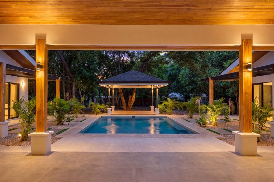 View from the covered terrace across the pool to the rancho at dusk
