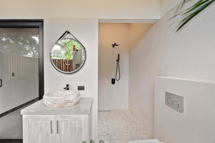 En-suite bath with carved-stone vessel sink and matte black fixtures