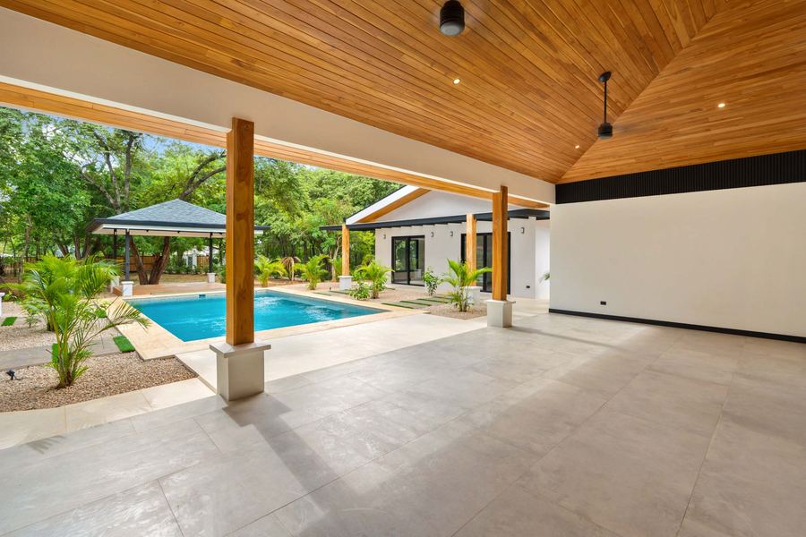Indoor-outdoor living space under a teak ceiling, open to the pool terrace