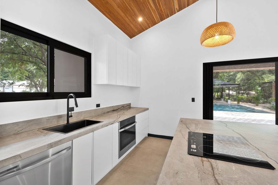 Kitchen counters in natural stone with a picture window to the pool